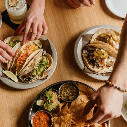 Hands grasping at delicious tacos, nachos and salsa at el diablo kingsville